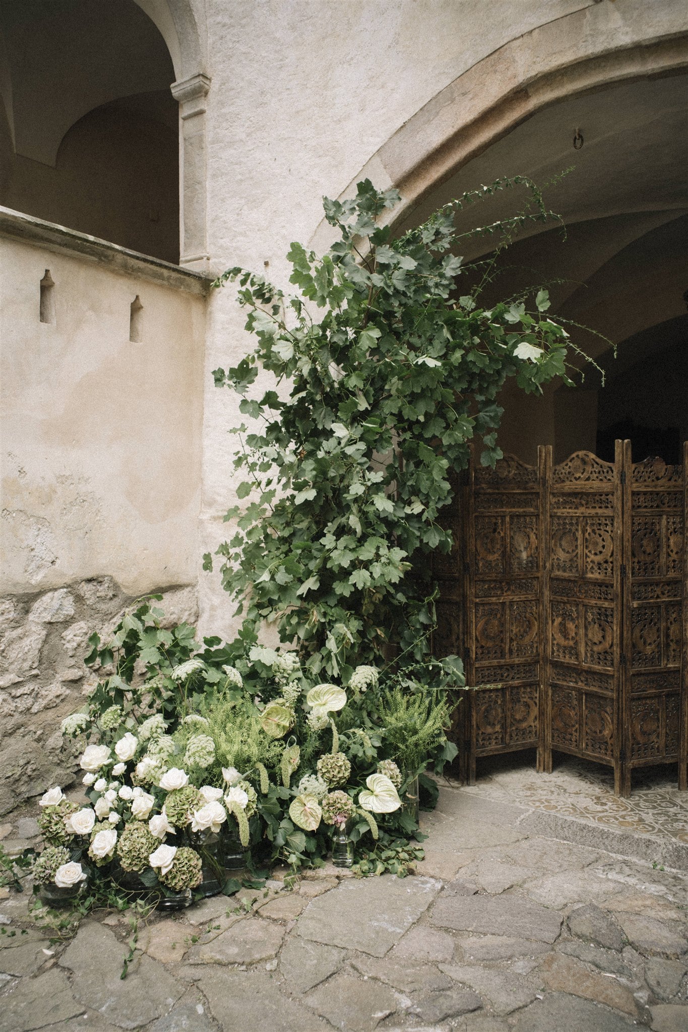 Nahaufnahme eines Blumengestecks mit Hydrangeas und grünen Blättern, arrangiert in rustikaler Umgebung.