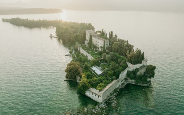 Sonnenuntergangsaufnahme einer idyllischen Insel mit einer luxuriösen Villa, mediterranen Gärten und einer zauberhaften Atmosphäre.