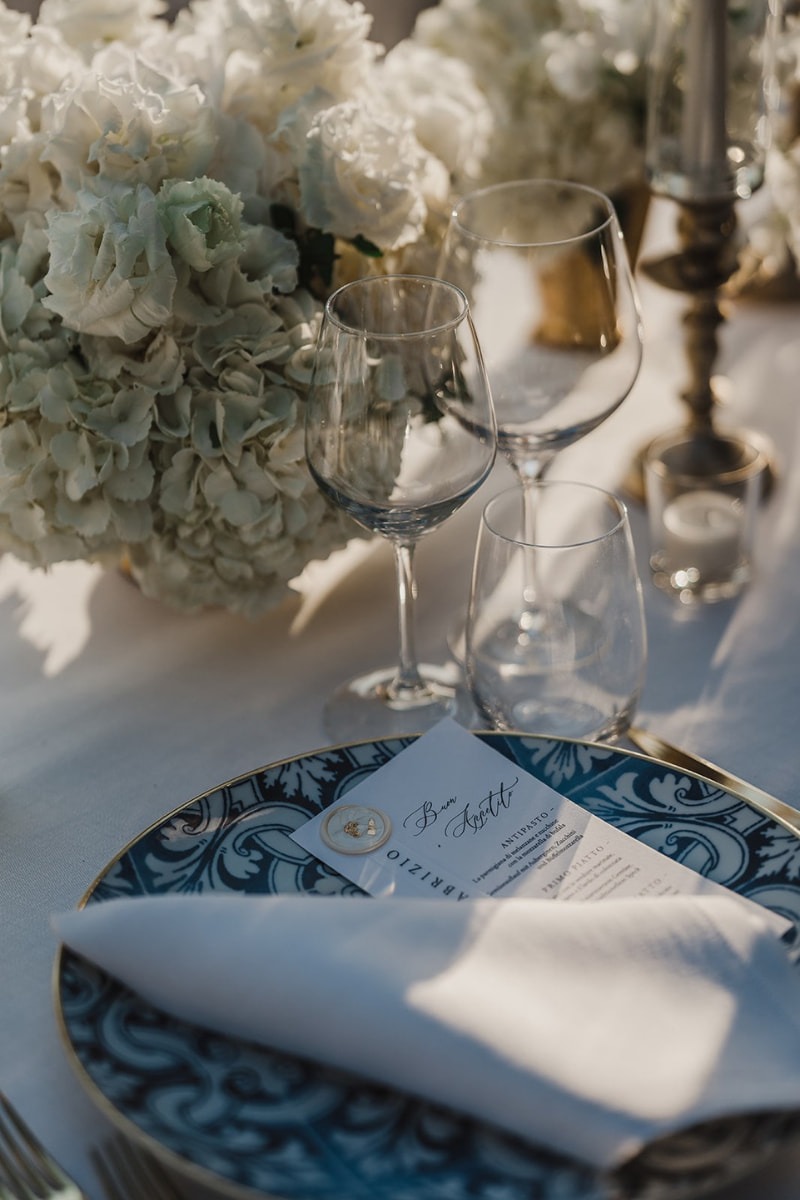 Detailaufnahme einer Hochzeitstafel mit blauem Porzellangeschirr und stilvollen Kerzenleuchtern.