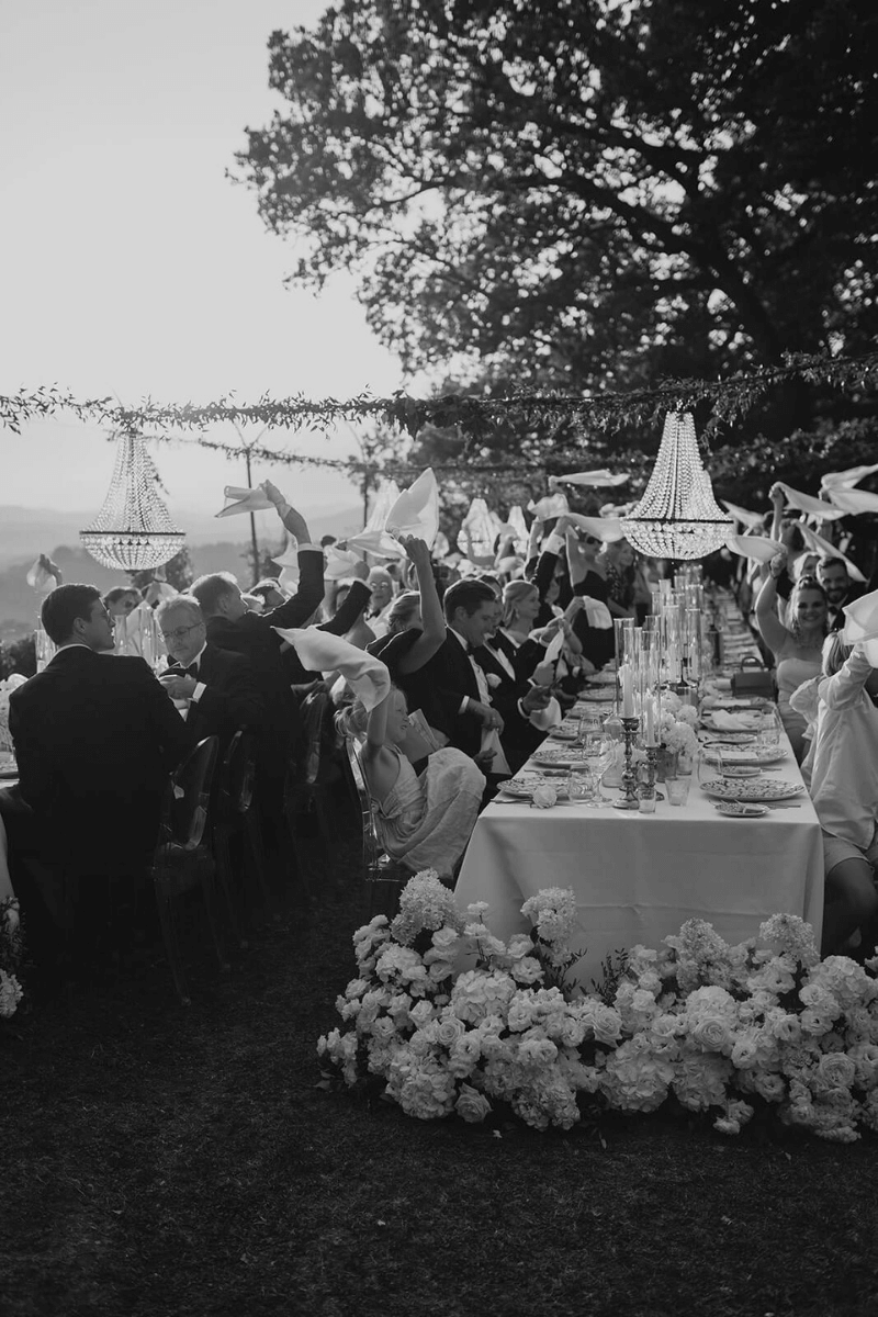 Schwarz-weiß Foto von feiernder Hochzeitsgesellschaft an Hochzeitstischen